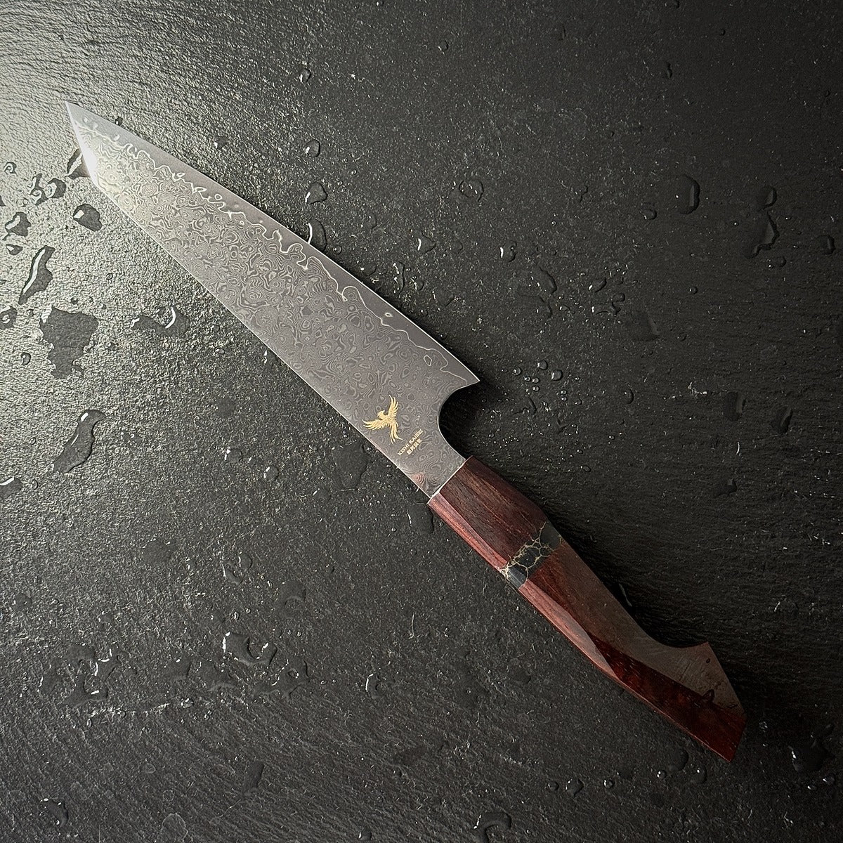 Couteau Petty à pointe biseautée, lame en acier damassé 10Cr15CoMoV, manche en bois de santal, posé sur ardoise